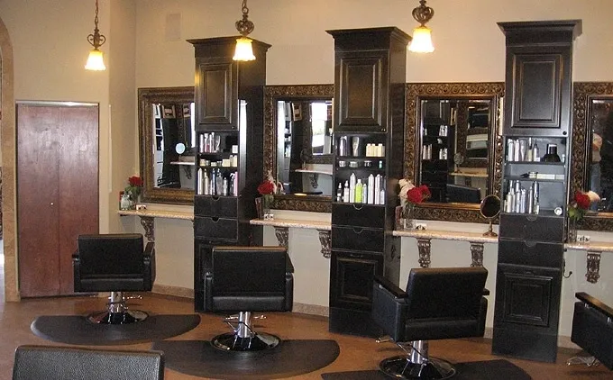 A hair salon with many black chairs and mirrors