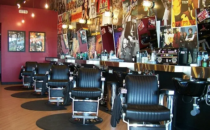 A barber shop with many black chairs and mirrors